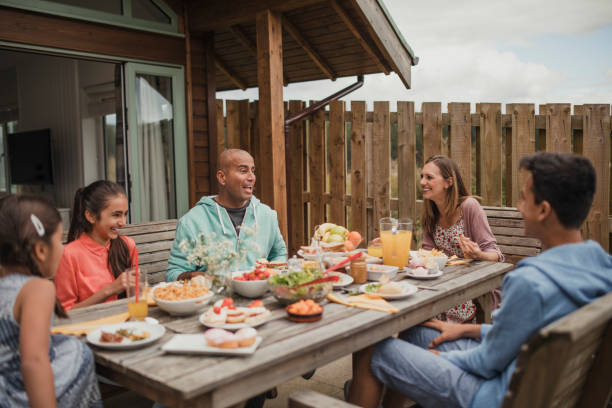 Family Breakfast Outside Holiday Cottage Family bonding and laughing, sitting having breakfast outside holiday cottage. egyptian ethnicity stock pictures, royalty-free photos & images