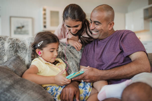 Father and Daughters Using a Digital Tablet Father and his two daughters using and looking at the digital tablet and laughing. north african ethnicity stock pictures, royalty-free photos & images