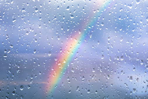 Rainbow through a window with drops after storm