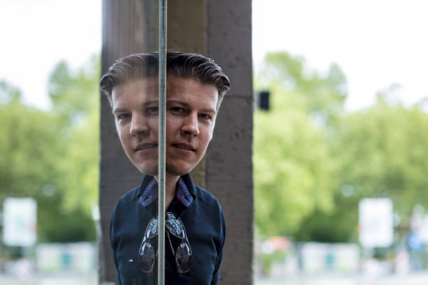 istock Man Posing in Front of Window Reflecting His Image 918954940