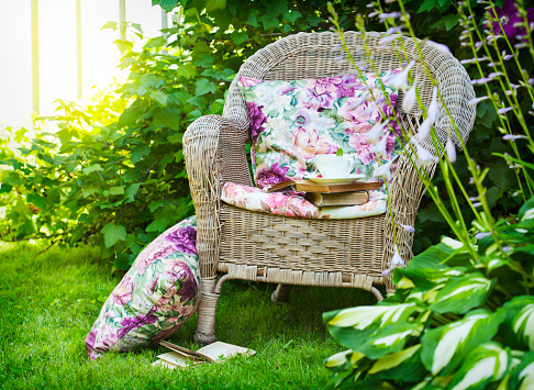 Cup of tea with a books on a chair in the garden.
