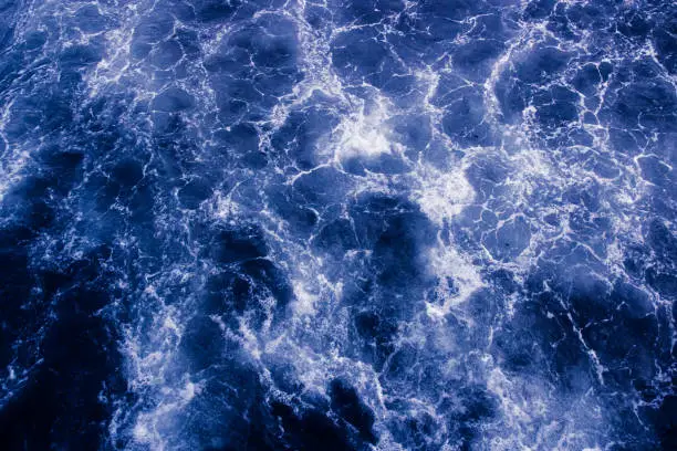 Photo of The surface of the sea with waves, foam and bubbles, blue abstract background