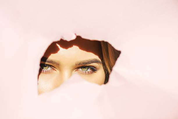 istock young woman looking at camera through torn pink paper 918985738