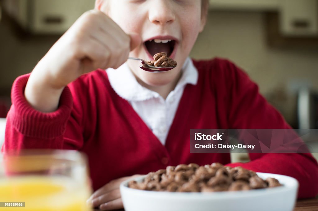 Close Up Of Girl Wearing School Uniform Eating Bowl Of Sugary Breakfast Cereal In Kitchen Child Stock Photo