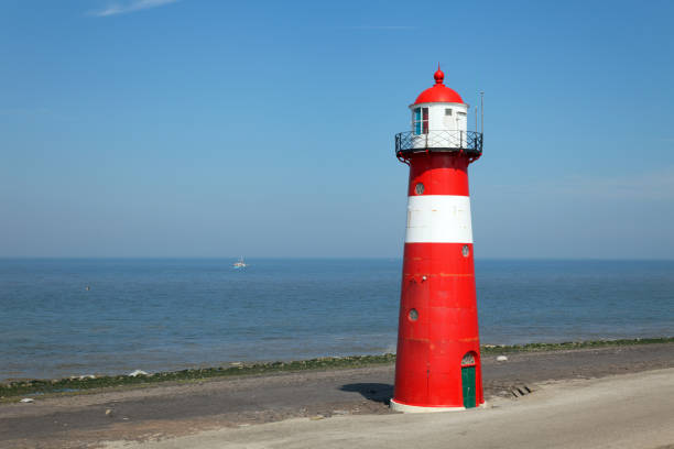 istock Red lighthouse on a dyke seawall by the blue sea 918989900