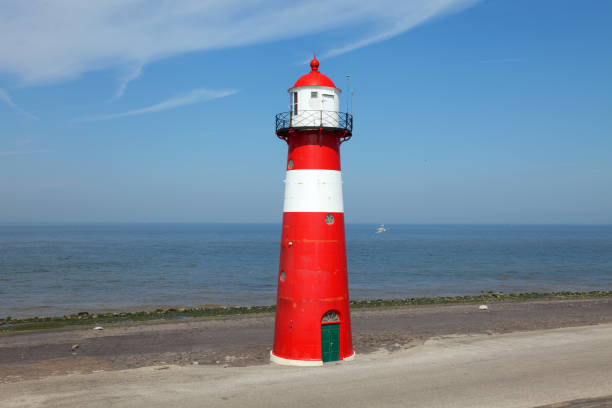 istock Red lighthouse on a dyke seawall by the blue sea 918989924
