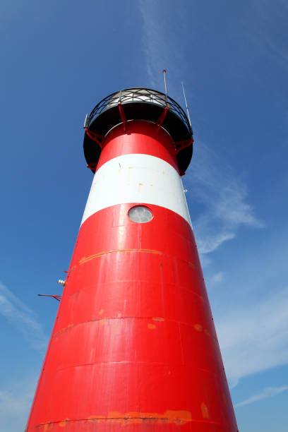 istock Red lighthouse on a dyke seawall by the blue sea 918990084