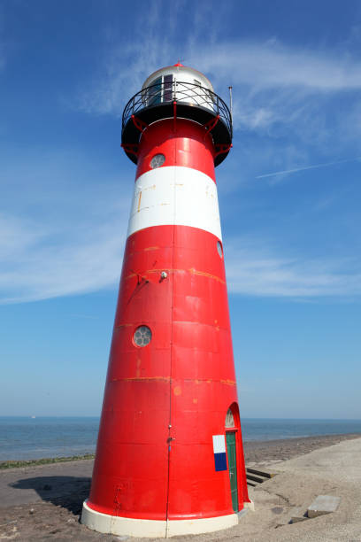 istock Red lighthouse on a dyke seawall by the blue sea 918990088
