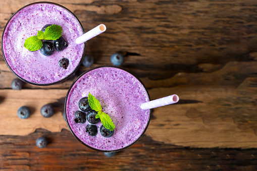 Blueberry smoothies on wooden floor from top view.