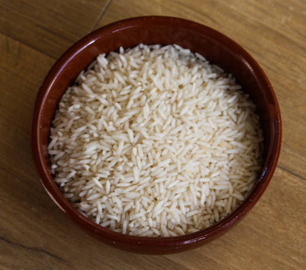istock Stone bowl with uncooked white rice on wooden background 919007352