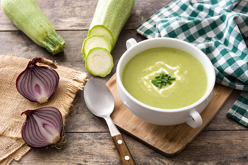 Zucchini soup in bowl on wooden table