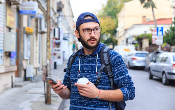 istock Young man with smart phone and coffee on street 919109644