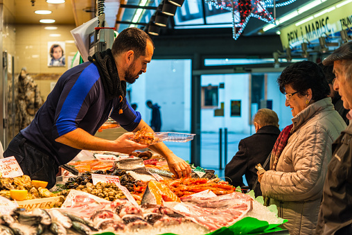 Barcelona, Spain - December 5, 2016: Vendor sells fish and seafood on the Santa Catarina Market, located in the neighborhood of Sant Pere and is the oldest covered market in Barcelona, Spain.