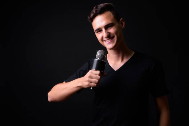 istock Handsome Man Singer With Microphone Against Black Background 919176210