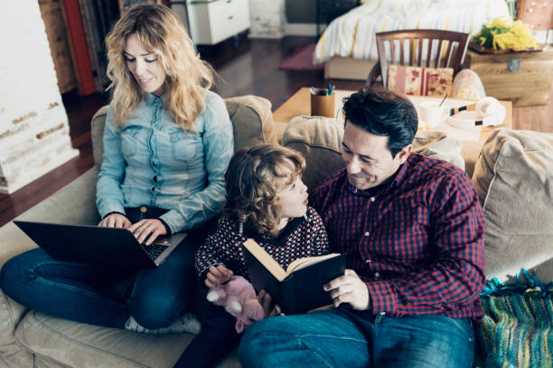 istock Father and his child reading book and mother working 919198792