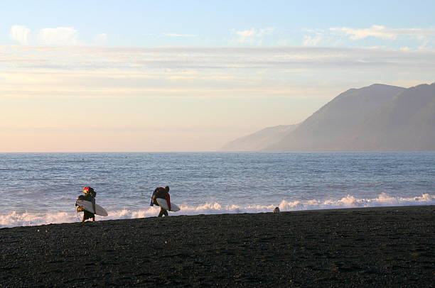 Beach, landscape and silhouette of surfer at sunset for adventure on holiday or vacation in summer. Ocean, surf and person with board in tropical Hawaii waves for travel, journey and relax in water