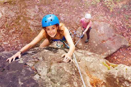 High angle view portrait of young woman, rock climber in helmet, trying to reach the top of the mountains