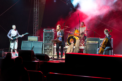 Rock band consisting of four members is playing on the concert stage in the summer.