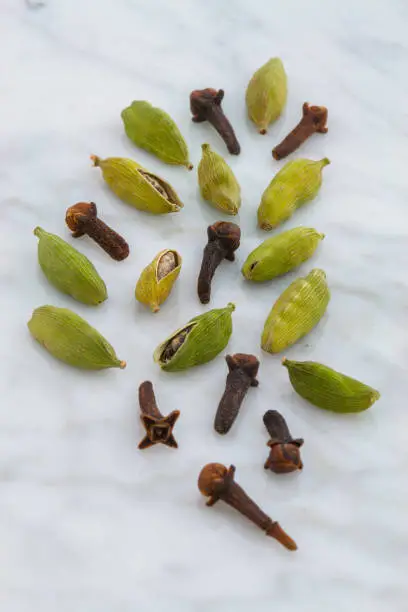 beautiful cardamom pods and cloves on top of carrara marble coutertop