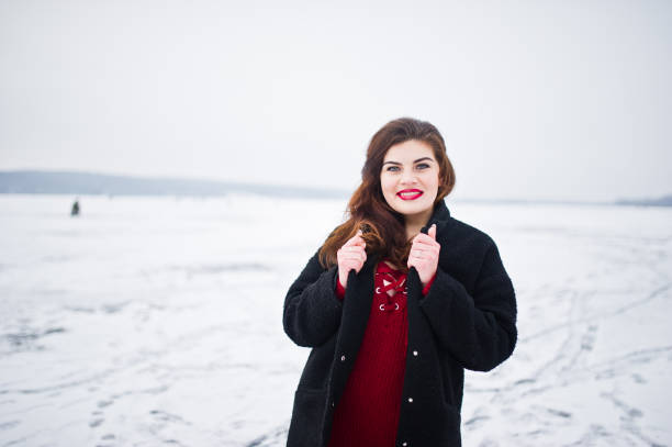 istock Brunette plus size model at red against frozen lake on winter day. 919313564