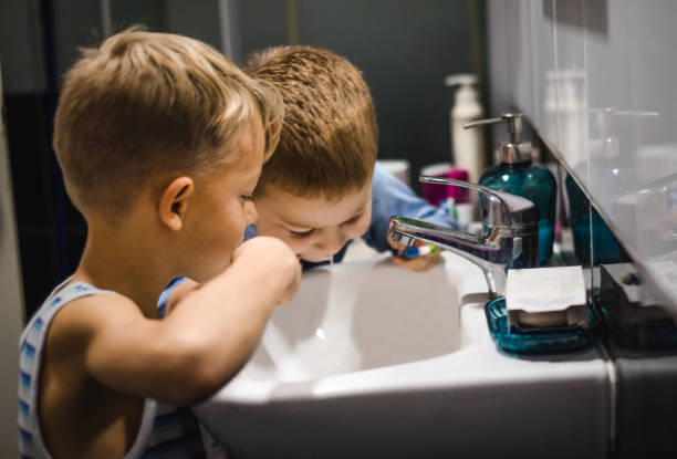 istock Two small boys washing teeth together in bathroom 919362008