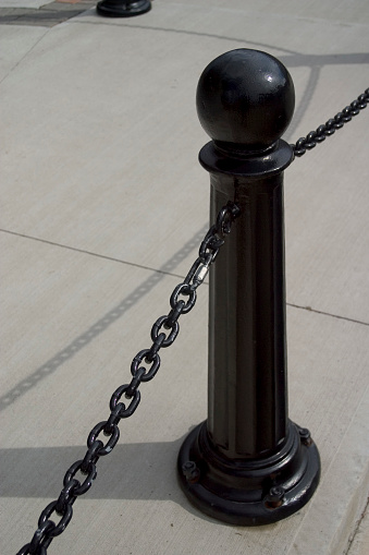 Black steel post with chain hanging from it.