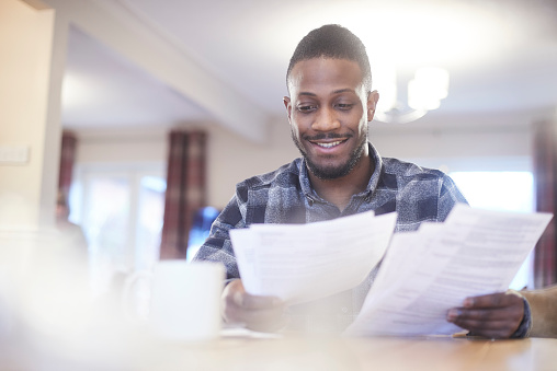 Young black male reading through some paperwork at home