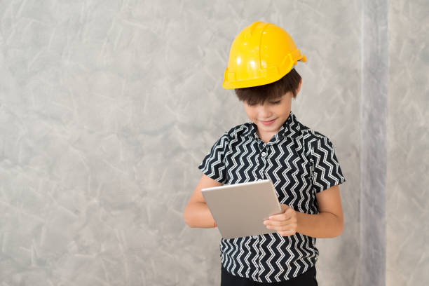 istock A boy wearing a yellow safety helmet are working with a digital tablet. 919402196