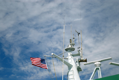 Old Glory flies amidst the communications and sensor equipment of a ship.