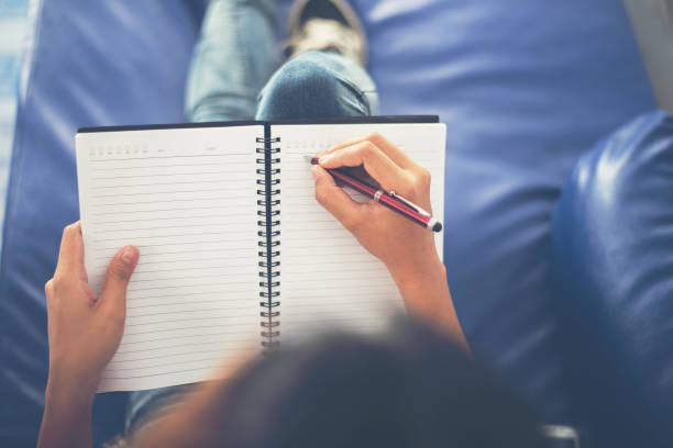 istock Woman hands writing on notepad lying at home . 919418384