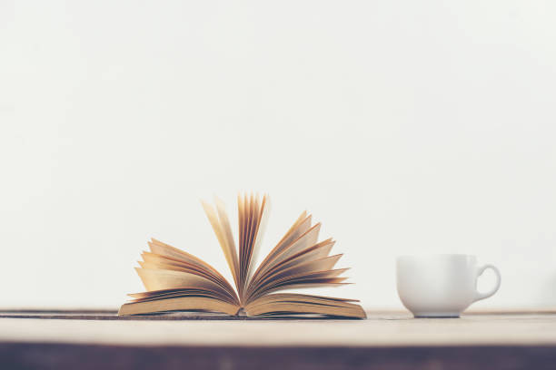istock Vintage old book with coffee cup on wooden deck table background. 919420516