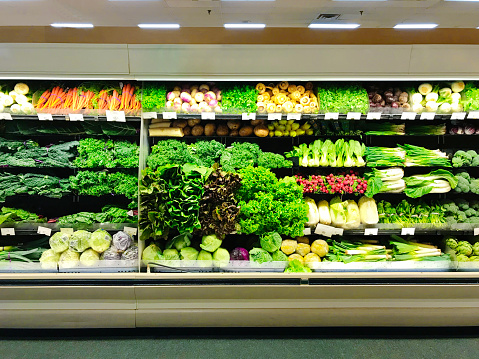 A display of fresh produce in a retail refrigerator case in grocery store. A variety of vegetables are presented to customers.