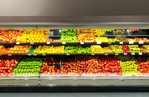A display of fresh produce in a retail refrigerator case in grocery store. A variety of fresh fruits are presented to customers.