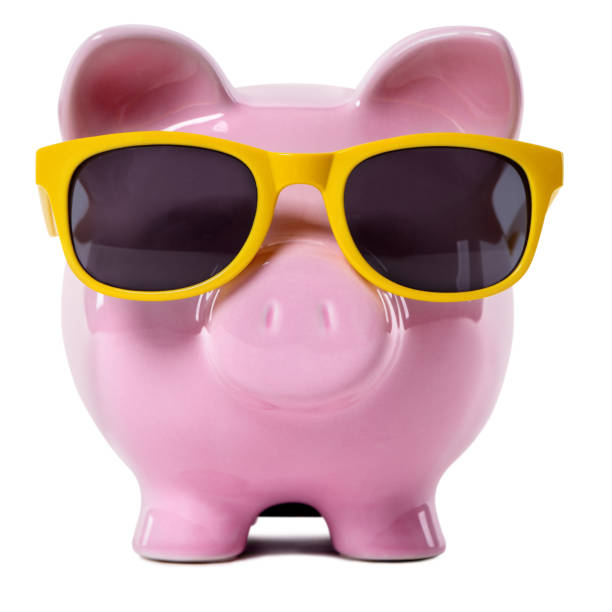 Pink piggy bank wearing yellow sunglasses. - fotografia de stock