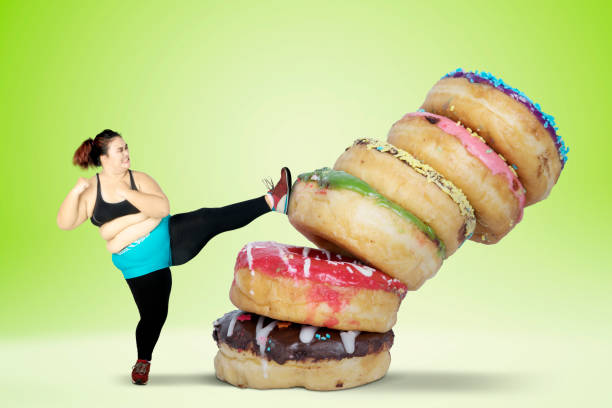 istock Overweight young woman kicking donuts 919458382