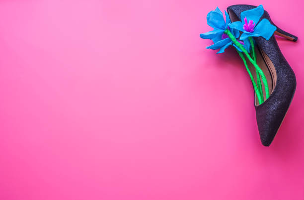 istock Woman's high heel shoe with blue spring paper flowers inside on pink background, top view. 919470840