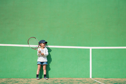 Little girl practicing tennis on the wall