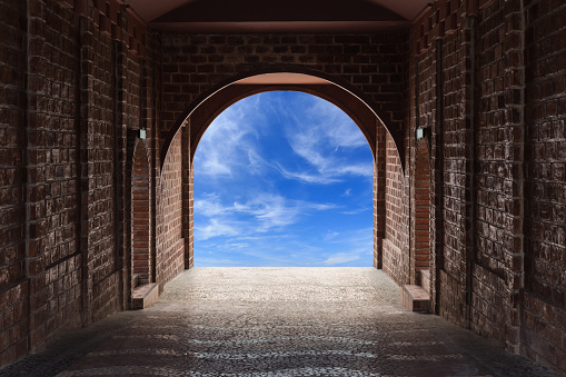 Walkway tunnel made by red brick and view of blue sky with cloud
