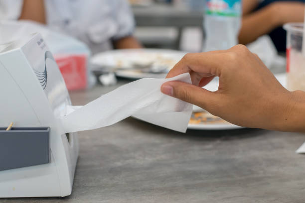 istock Woman hand pulling white tissue from a box on wooden table. 919501830