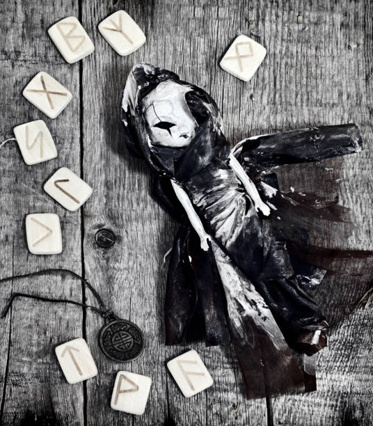 istock Scary doll with medallion and runes on witch table in black tone 919507226