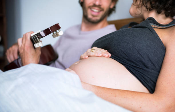 mann spielt gitarre für schwangere frau - lullaby stock-fotos und bilder