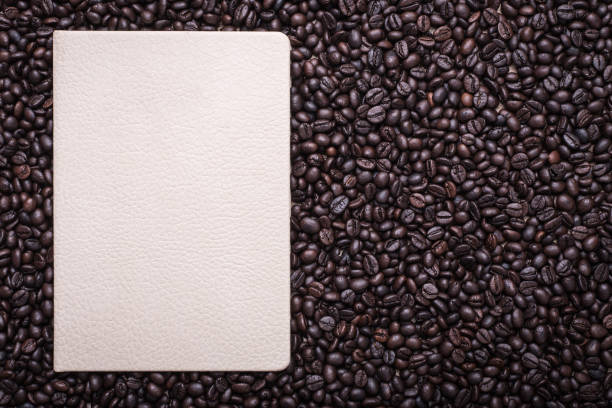 Coffee beans and note book on wooden background