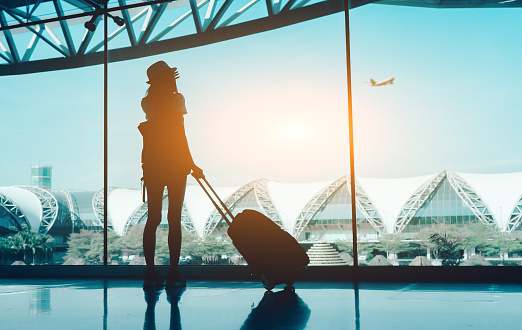 Silhouette woman travel with luggage looking without window at airport terminal international or girl teenager traveling in vacation summer relaxation holding suitcase and backpack