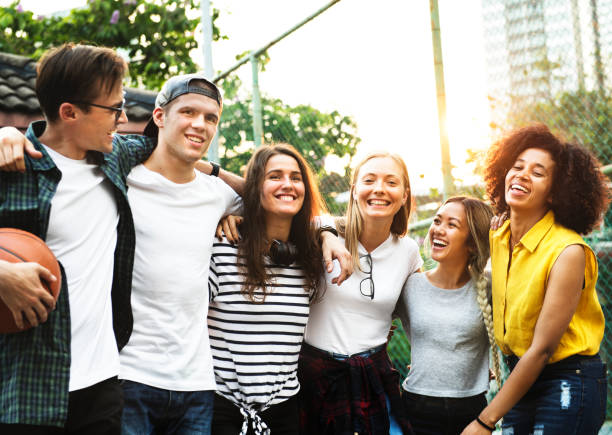Smiling happy young adult friends arms around shoulder outdoors friendship and connection concept Smiling happy young adult friends arms around shoulder outdoors friendship and connection concept international match stock pictures, royalty-free photos & images