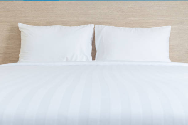 istock White bedding sheets and pillow in hotel room 919536392