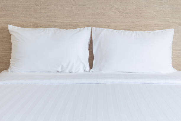 istock White bedding sheets and pillow in hotel room 919536444