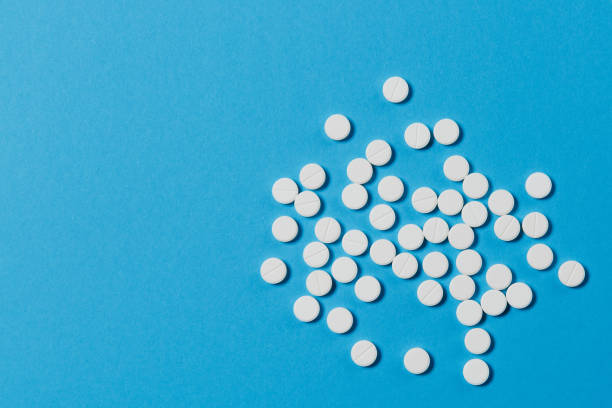 istock Medication white round tablets arranged abstract isolated on blue color background. Aspirin pills for design. Concept of health, treatment, choice, healthy lifestyle. Copy space for advertisement. 919539010