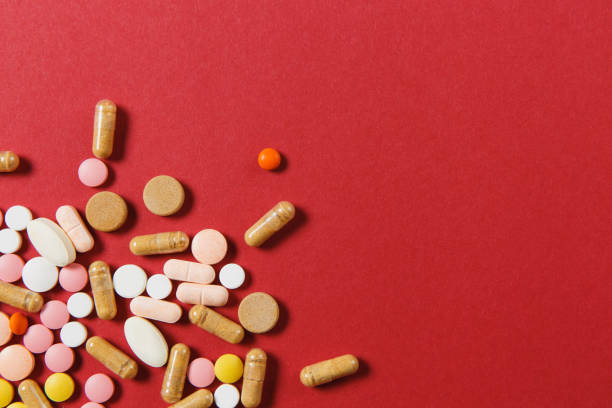 istock Medication white colorful round tablets arranged abstract on red color background. Aspirin, capsule pills for design. Health, treatment, choice healthy lifestyle concept. Copy space advertisement. 919542022