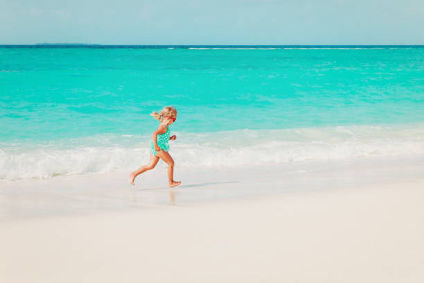 istock little girl run play with waves on the beach 919552142