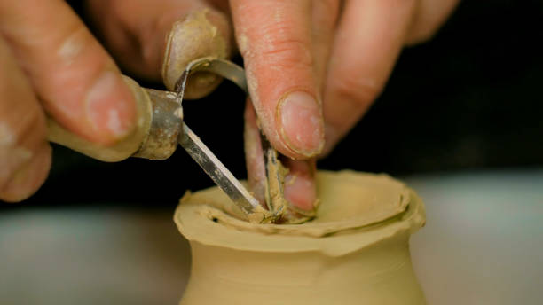 istock Professional potter carving mug with special tool in pottery workshop 919561060